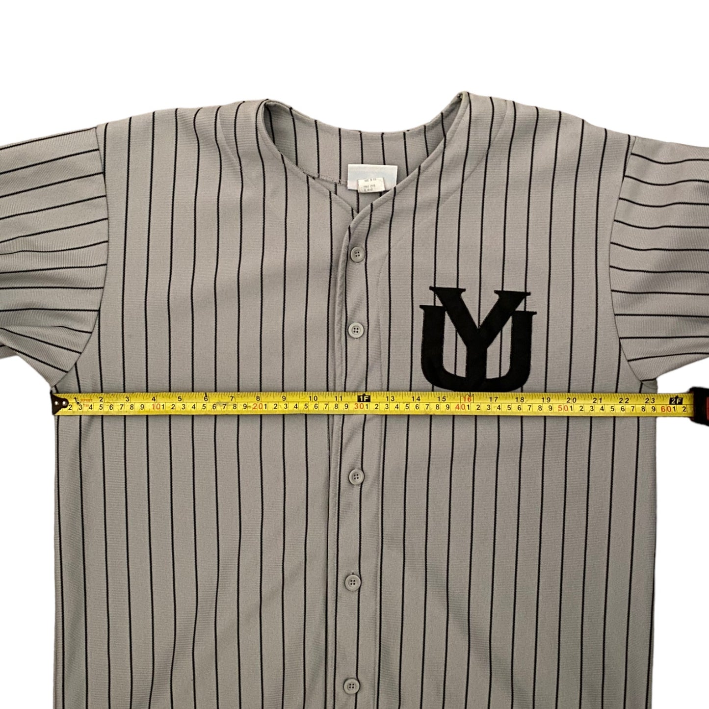 A gray pinstripe baseball jersey with a black 'YU' logo on the chest, shown with a yellow tape measure stretched horizontally across the chest to indicate width.