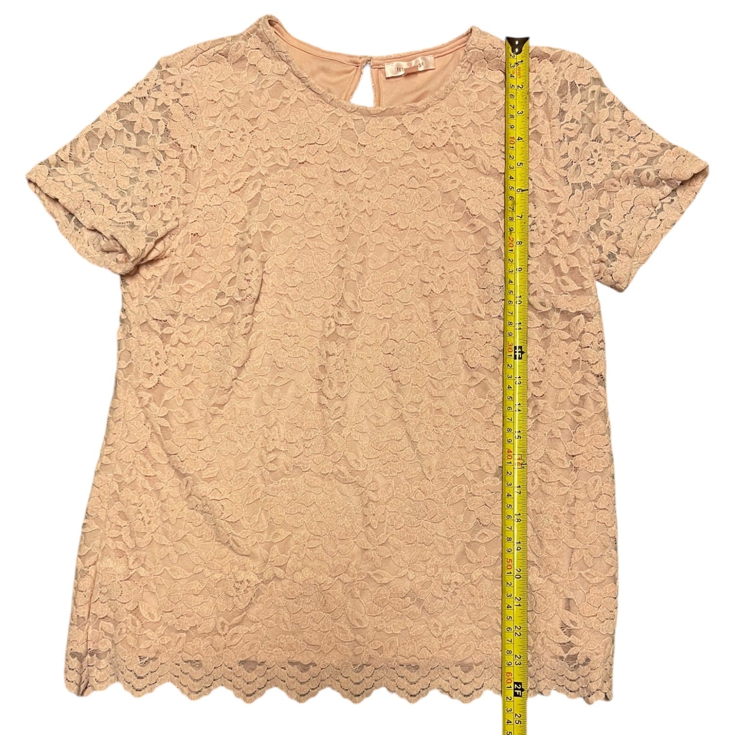 Pink lace top with a measuring tape on a white background