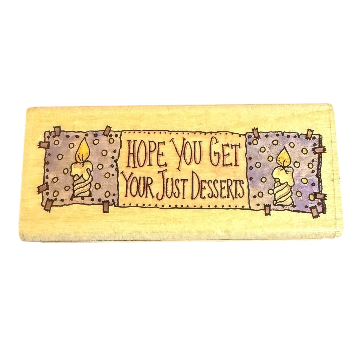 A rectangular block with a painted rustic design featuring two candles and the text 'HOPE YOU GET YOUR JUST DESSERTS' on a white background.
