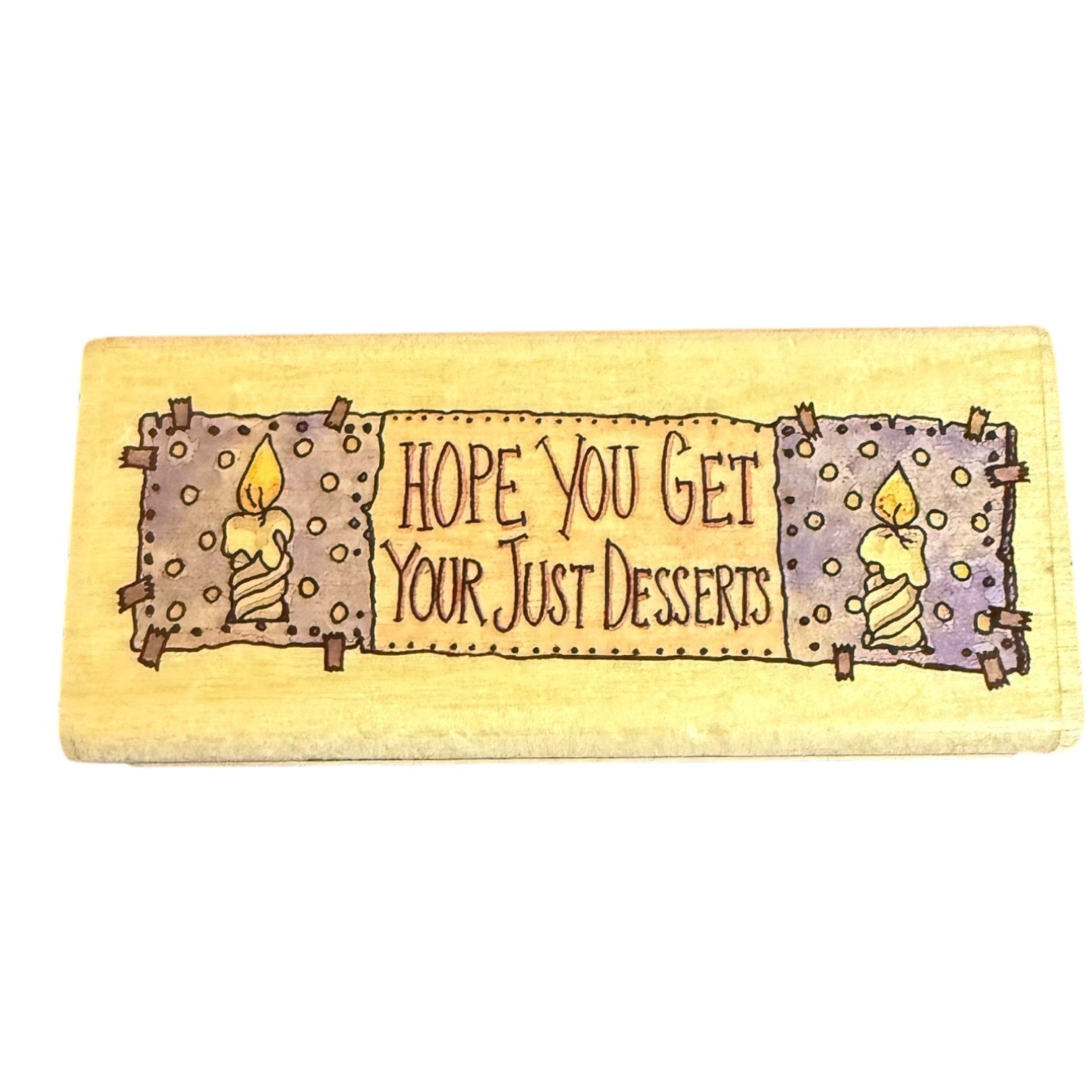 A rectangular block with a painted rustic design featuring two candles and the text 'HOPE YOU GET YOUR JUST DESSERTS' on a white background.