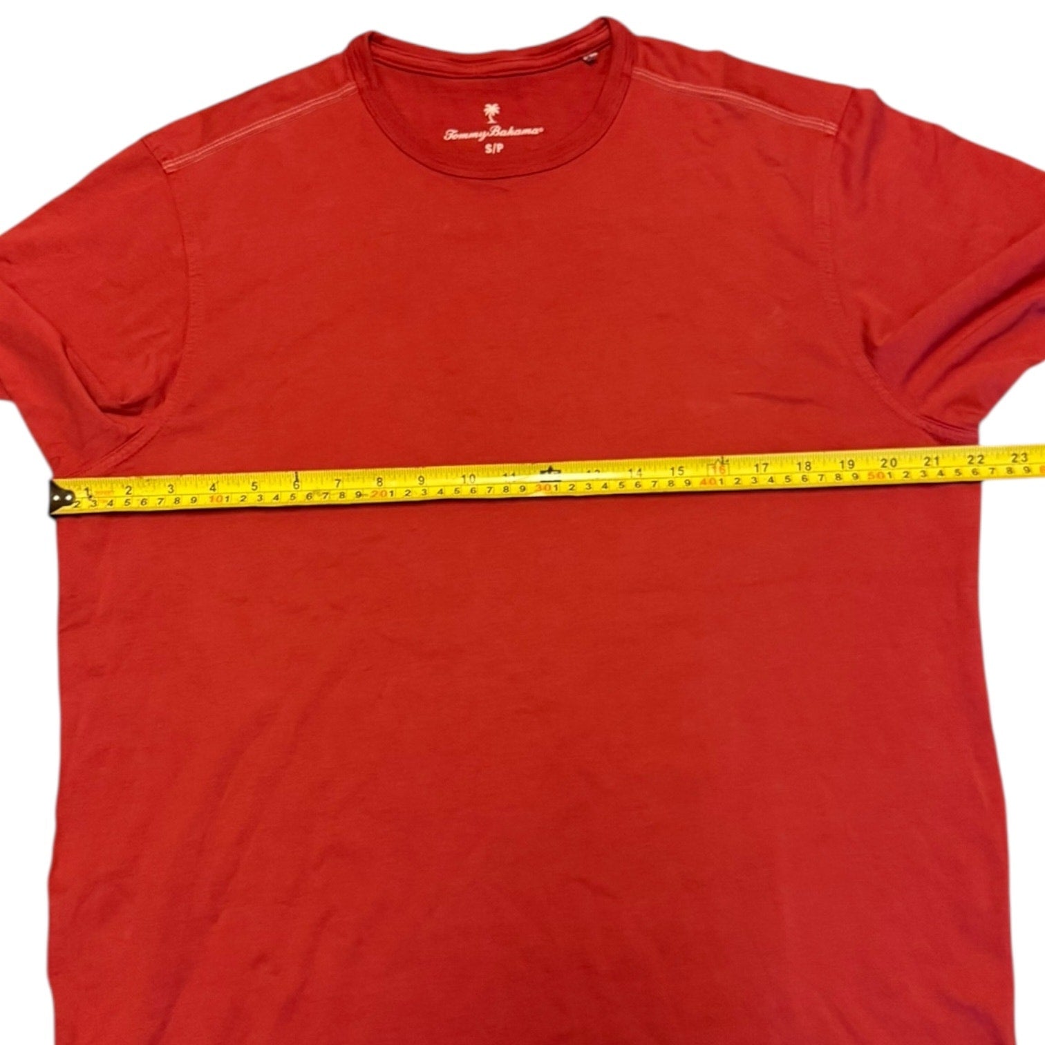 Red t-shirt with a measuring tape across it on a white background