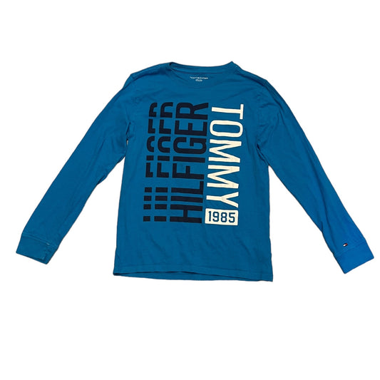 A blue long-sleeve crewneck t-shirt by Tommy Hilfiger, featuring a large vertical graphic print on the front with 'HILFIGER TOMMY 1985' in black and white.
