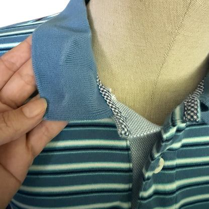 Close-up fading of a blue fabric strip being held over a striped shirt on a mannequin.