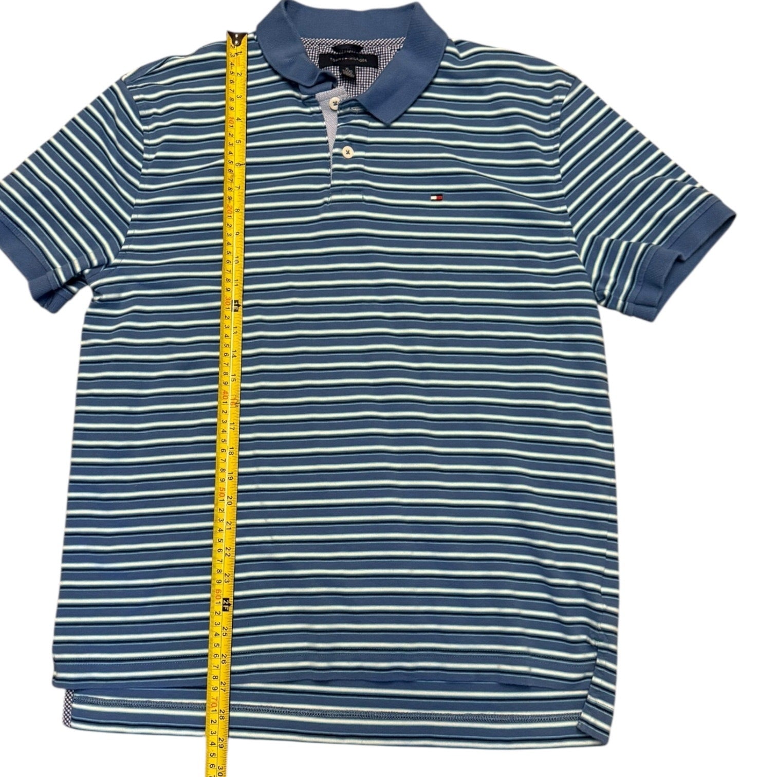 Blue and white striped polo shirt with a measuring tape on a white background