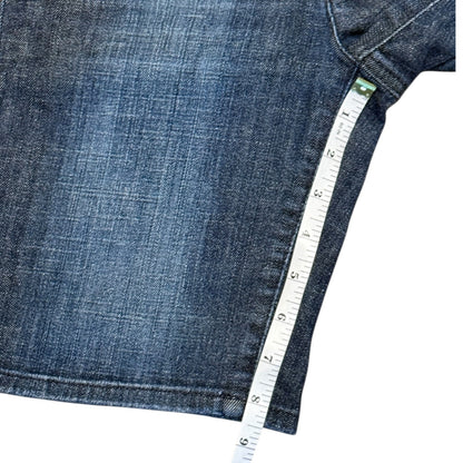 Close-up of a blue denim shorts with a white measuring tape running along the seam to show the measurement.
