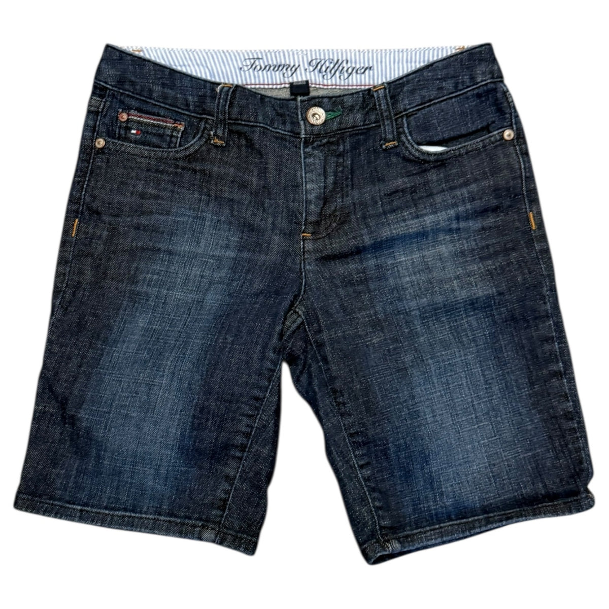 A pair of Tommy Hilfiger dark blue denim shorts with a faded wash, featuring the brand's signature embroidered logo on the inner waistband.