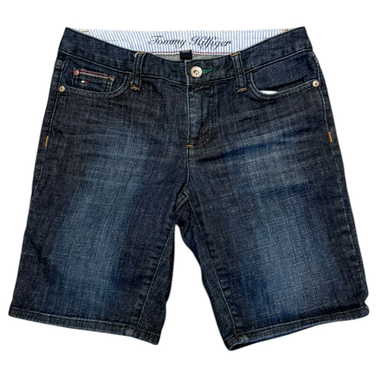 A pair of Tommy Hilfiger dark blue denim shorts with a faded wash, featuring the brand's signature embroidered logo on the inner waistband.