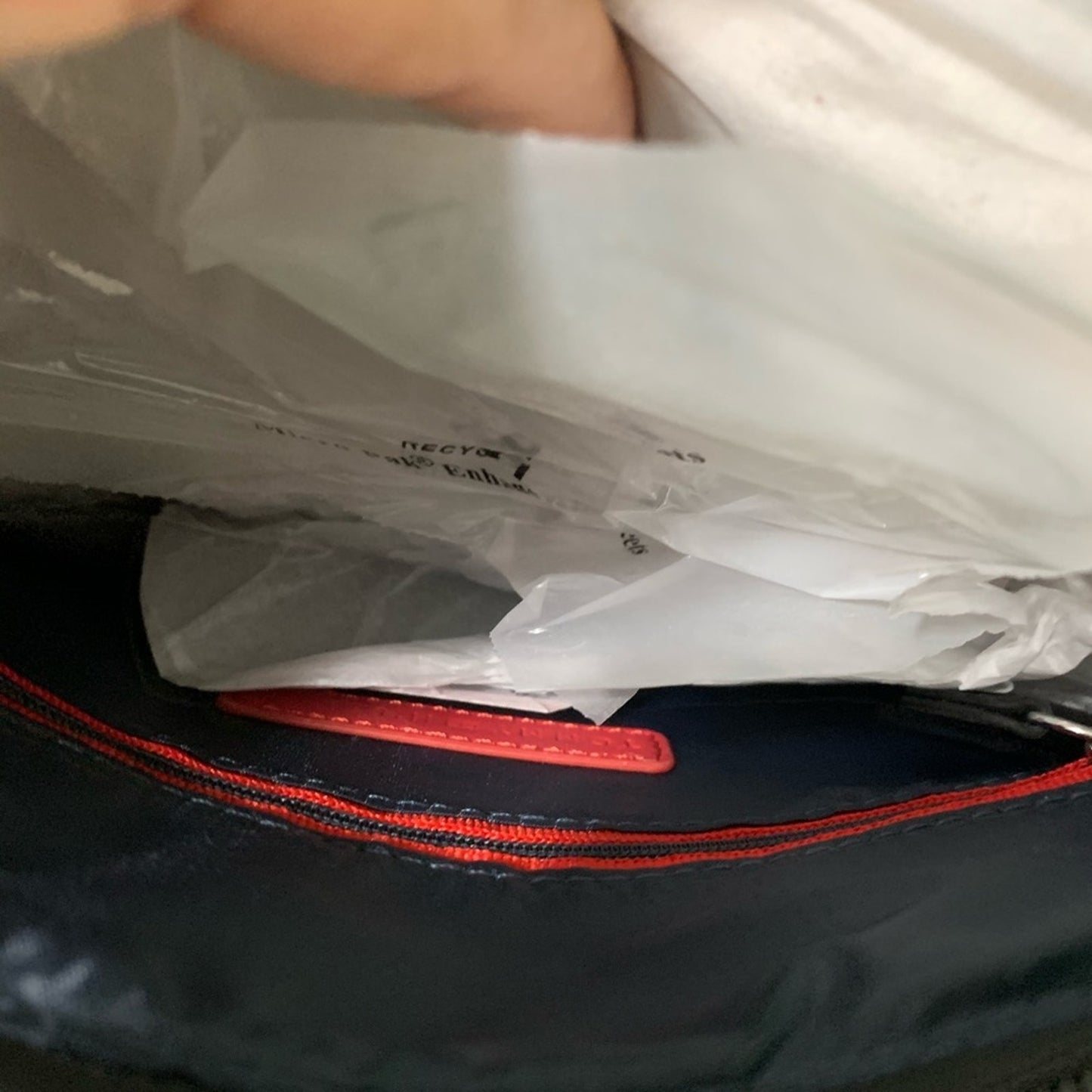 Close-up of a bag in Interior with red zipper and white plastic sheeting.