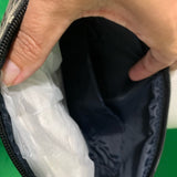Close-up of a hand holding a black bag with a green background