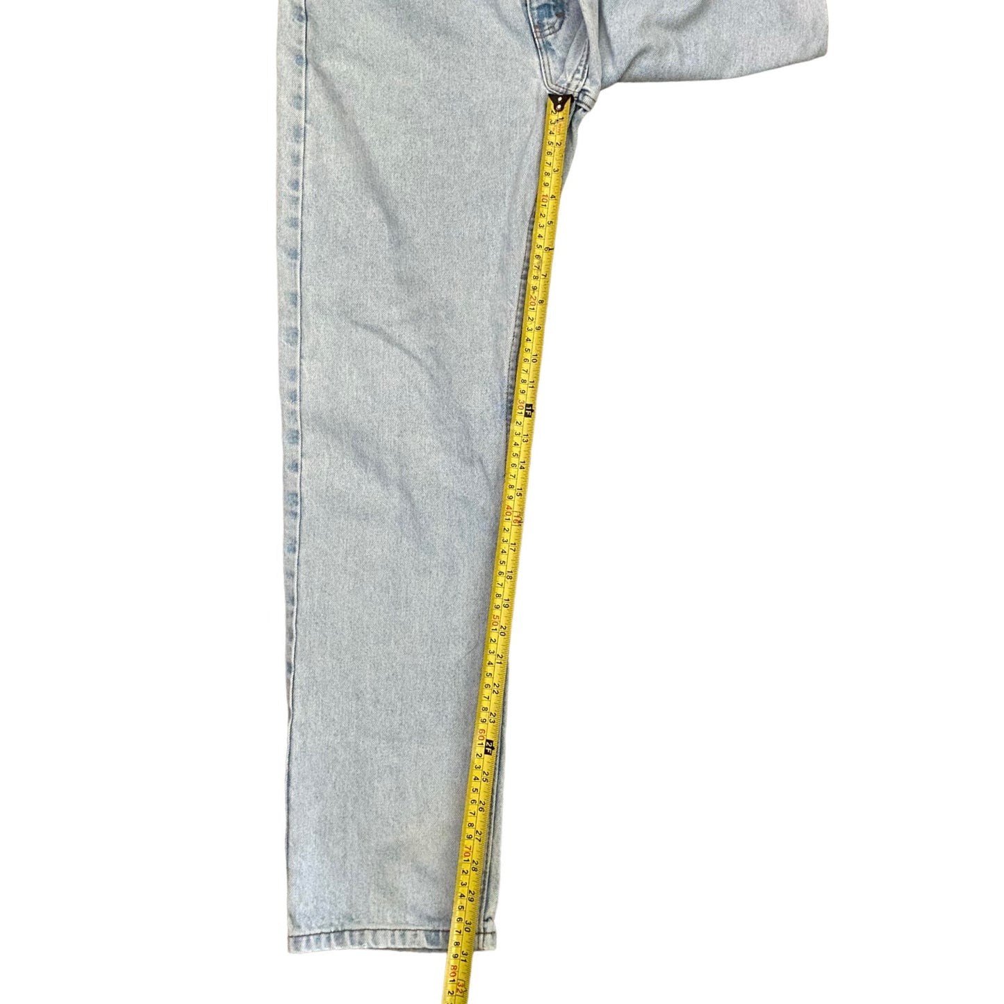 Light wash blue jeans shown with a yellow tape measure draped down the side to indicate the leg's length, on a solid white background.