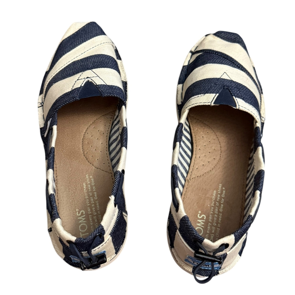 A pair of TOMS canvas slip-on shoes with navy blue and off white horizontal stripes, shown from both the top and side views against a white background.