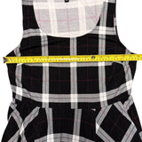 Black and white checkered dress with a measuring tape draped over it on a white background