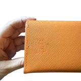 Hand holding a textured orange case with issues against a white background