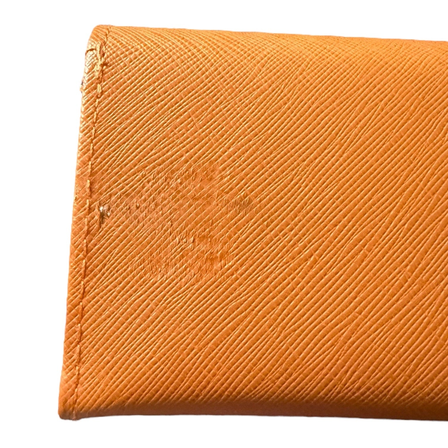 Close-up of an orange textured fabric with a brand logo showing issues