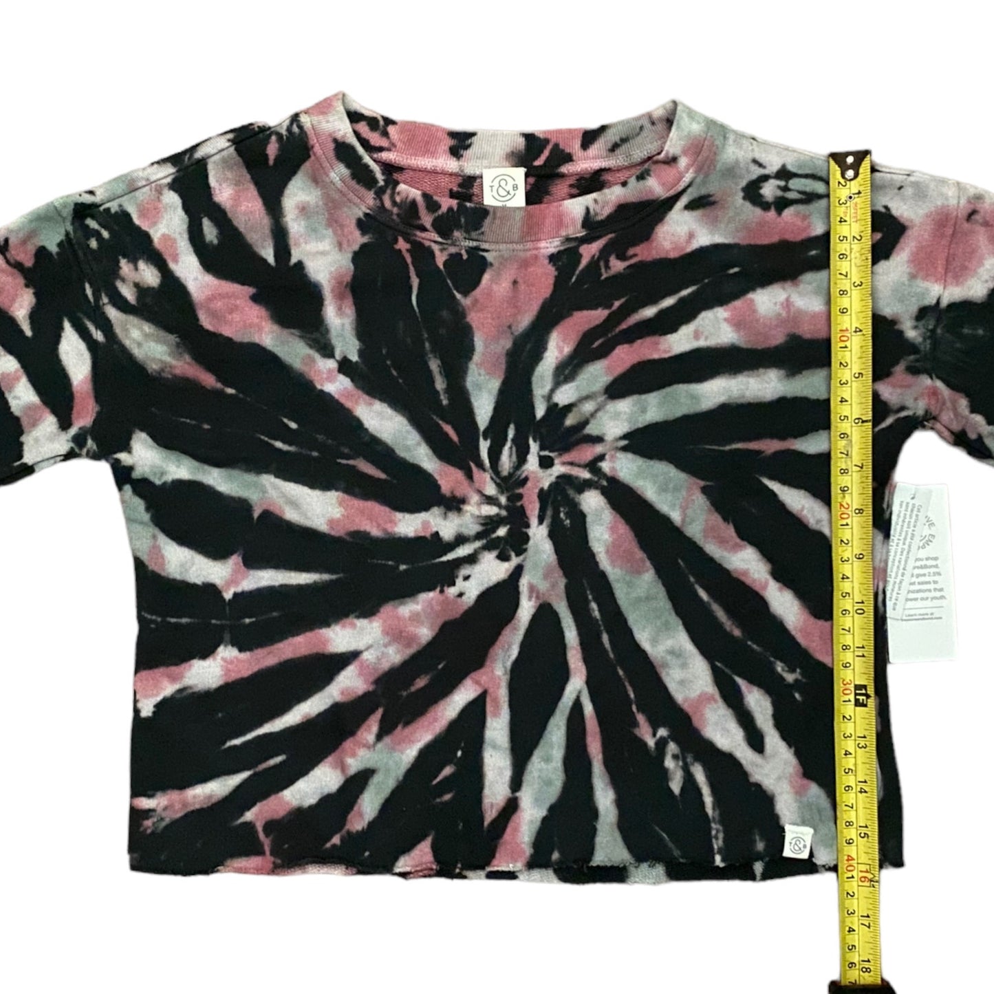 Tie-dye t-shirt with black, pink, and white pattern, measured with a tape measure.