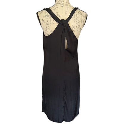 A sleeveless black dress from the back displayed on a cream-colored dress form mannequin against a plain white background.