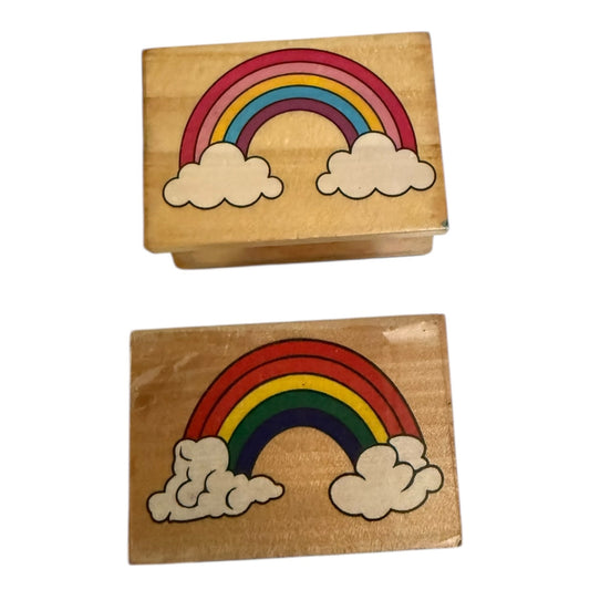 Two wooden stamps with rainbow and cloud designs on a white background