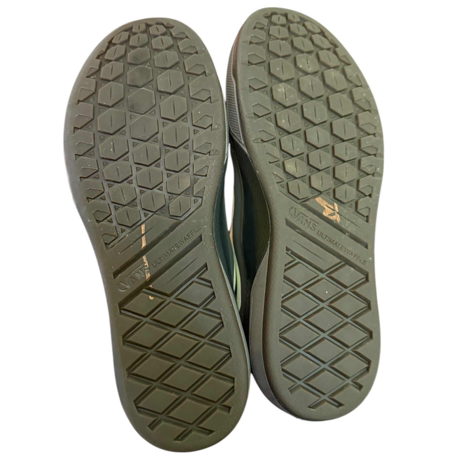 Close-up of the soles of a pair of shoes with a brand logo on a white background