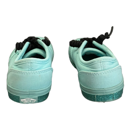 Back view of green sneakers with black laces on a white background