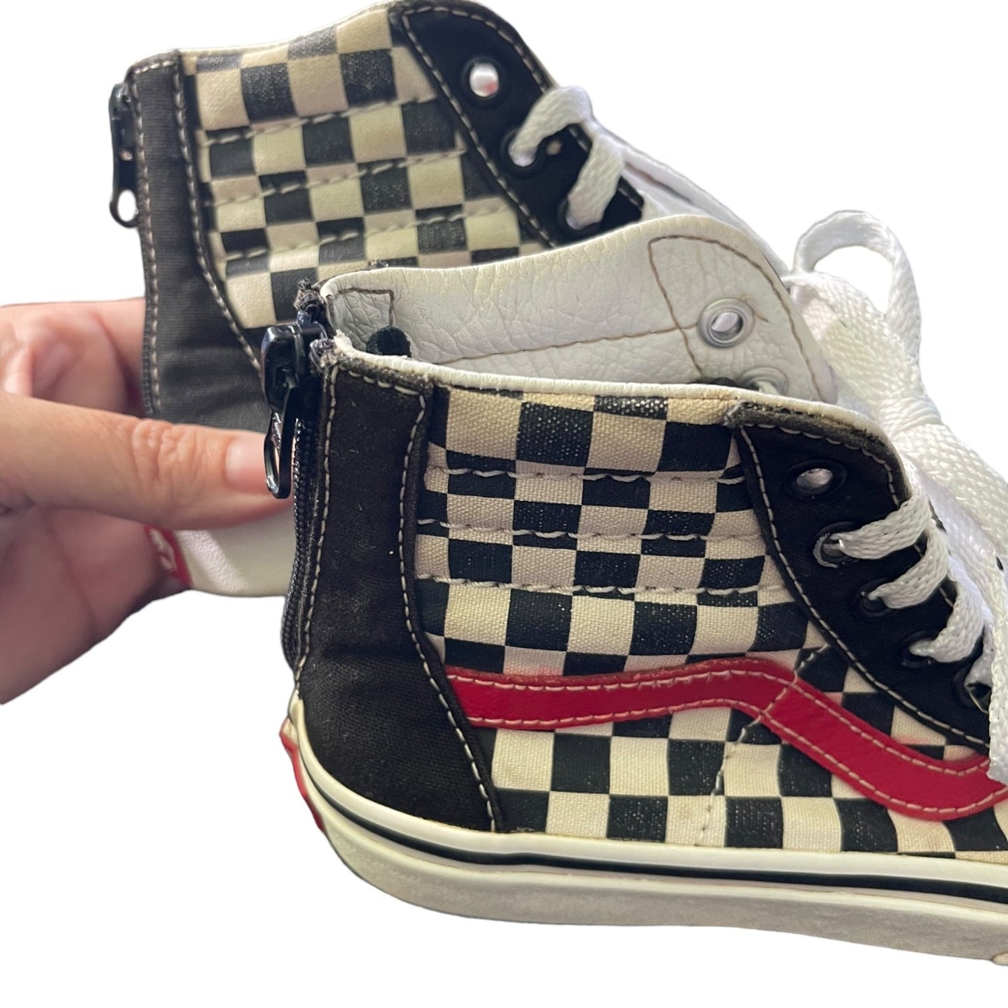 Checkered high-top sneakers with a red accent held by a hand on a white background