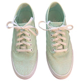 Front of a Pair of light green sneakers with white laces on a white background