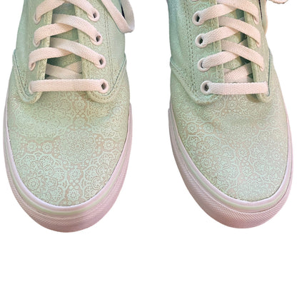 Close up of a Pair of light green sneakers with white laces on a white background