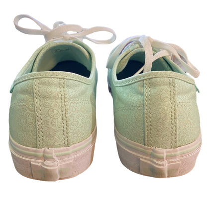 Back of a Pair of light green sneakers with white laces on a white background