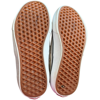 Close-up of the soles of a pair of shoes with brown waffle pattern on a white background