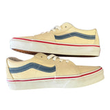 Side of cream sneakers with blue and red accents on a white background