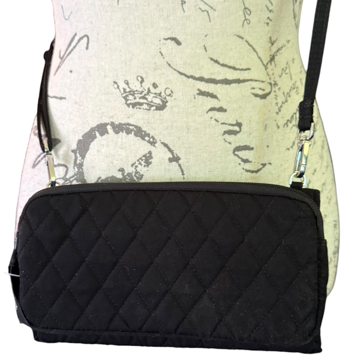 Back of black quilted purse on a mannequin on a white background. 