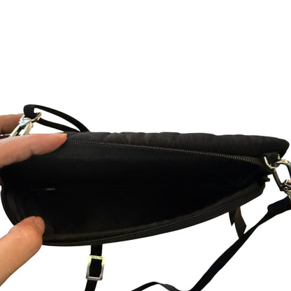 Hand holding open a black purse with a zippered pocket, showing that pocket open on a white background. 