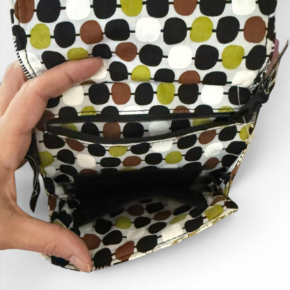 Polka dot patterned interior of bag with a hand opening it on a white background