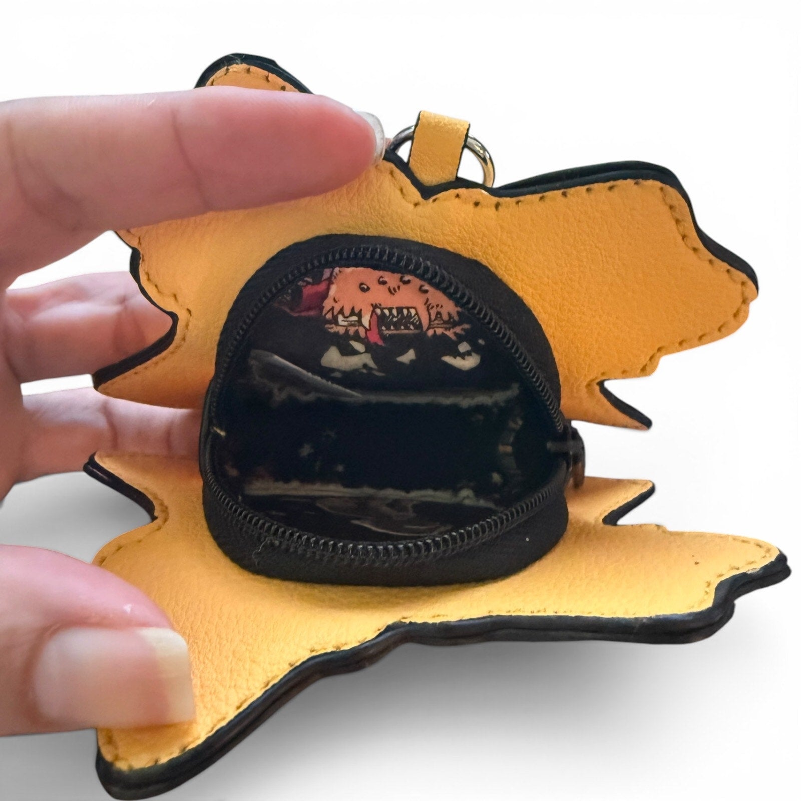 Yellow pouch with a black interior, held open by a hand on a white background