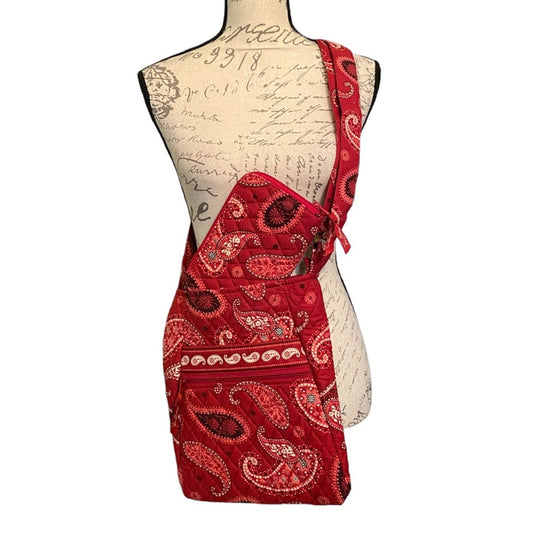 Red paisley crossbody bag with a single shoulder strap, wallet, displayed on a vintage-style printed dress form mannequin against a white background.