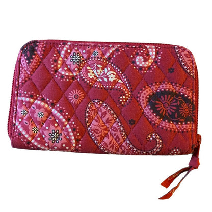 A quilted zip-around wallet in a vibrant red and pink paisley pattern, featuring a diamond-quilted texture and matching red zipper pulls, shown on a plain white background.