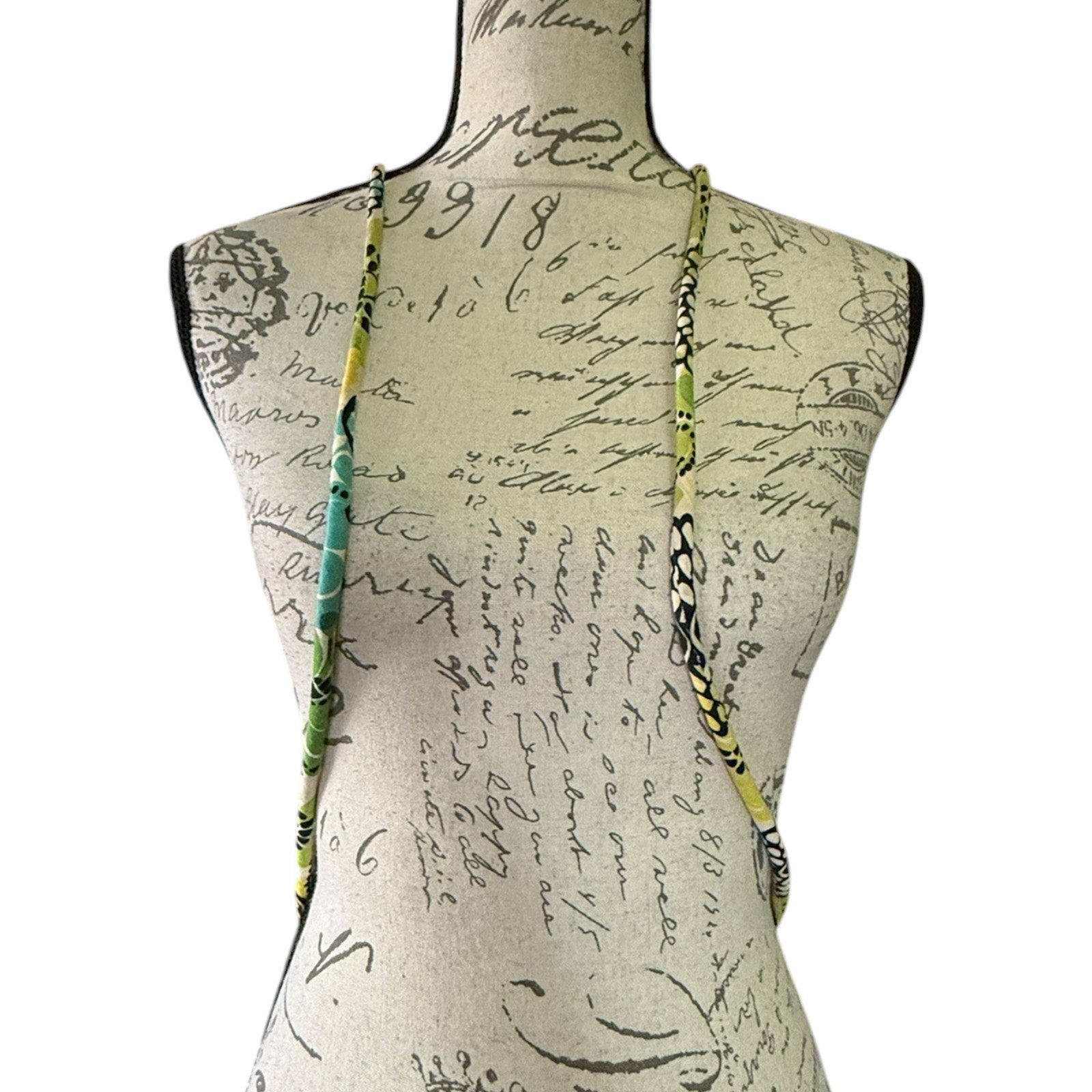 Straps of green floral packback on a background with text and graphics.