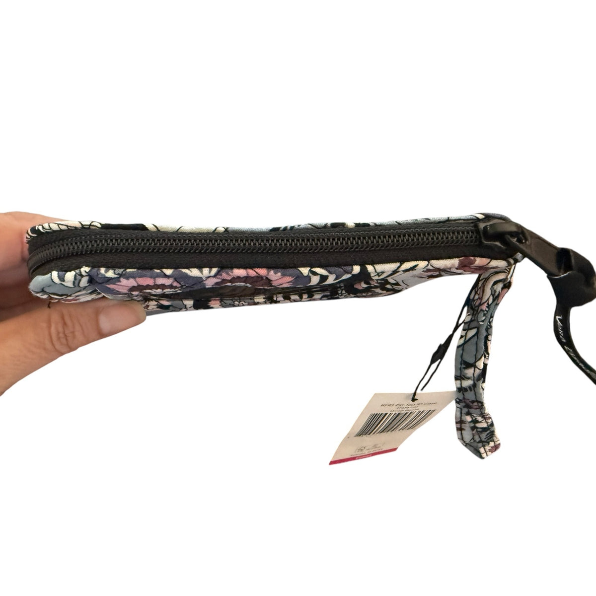 Top of Floral-patterned pouch wristlet with a strap held by a hand on a white background