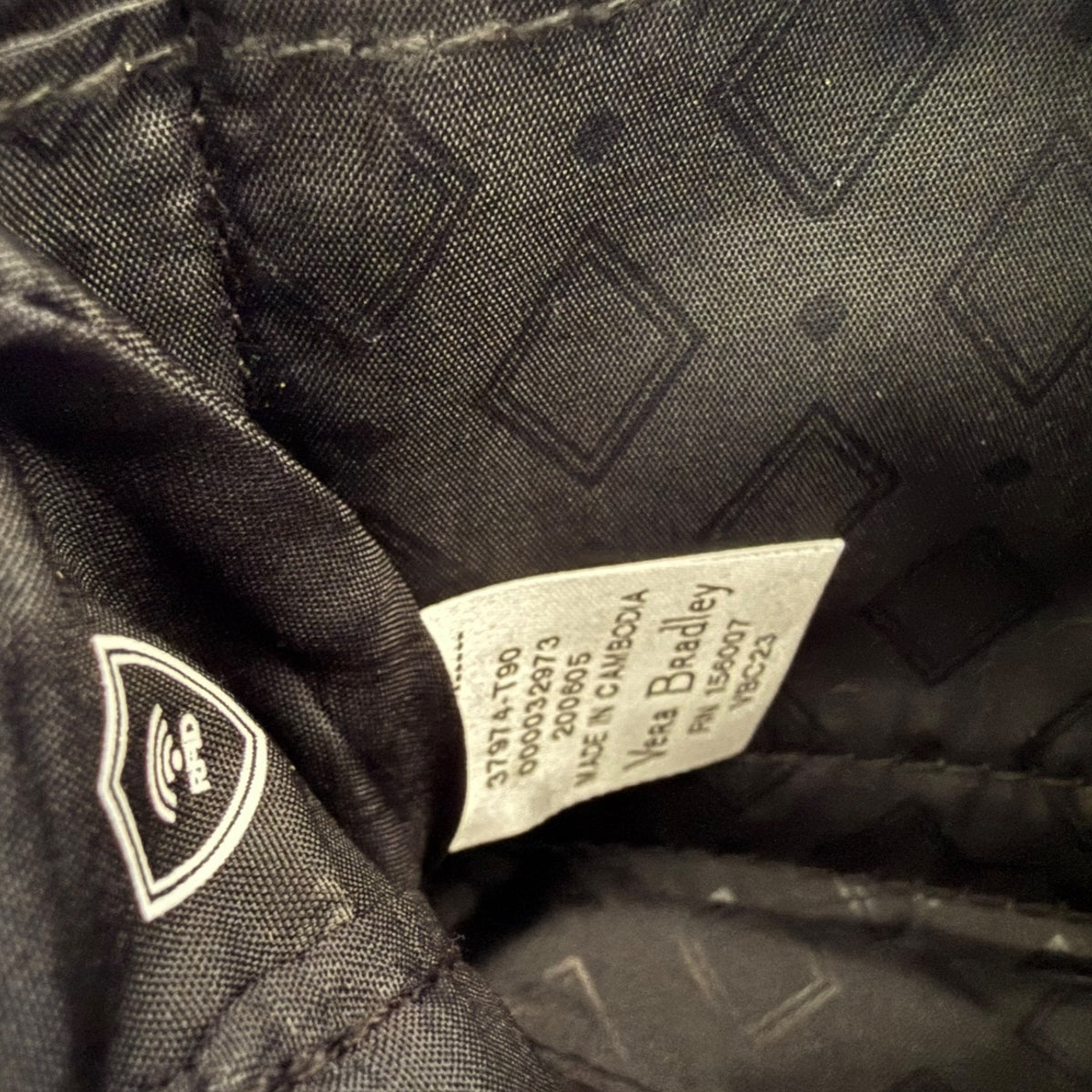 Close-up of a label on a interior black textured fabric with a brand logo.