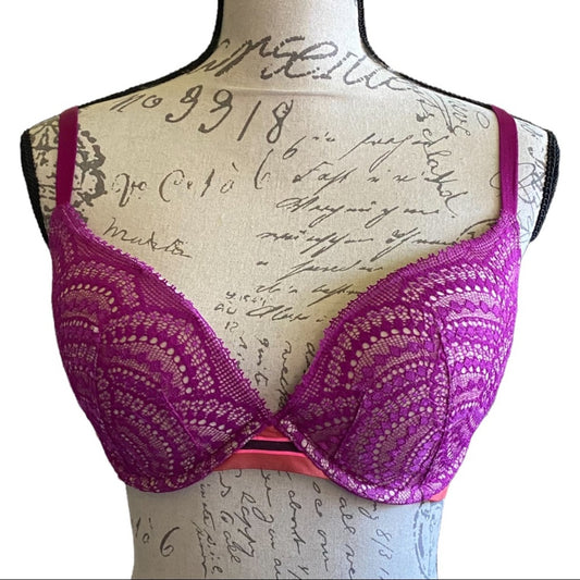 A lace bra displayed on a beige fabric mannequin torso with cursive writing, against a plain white background.