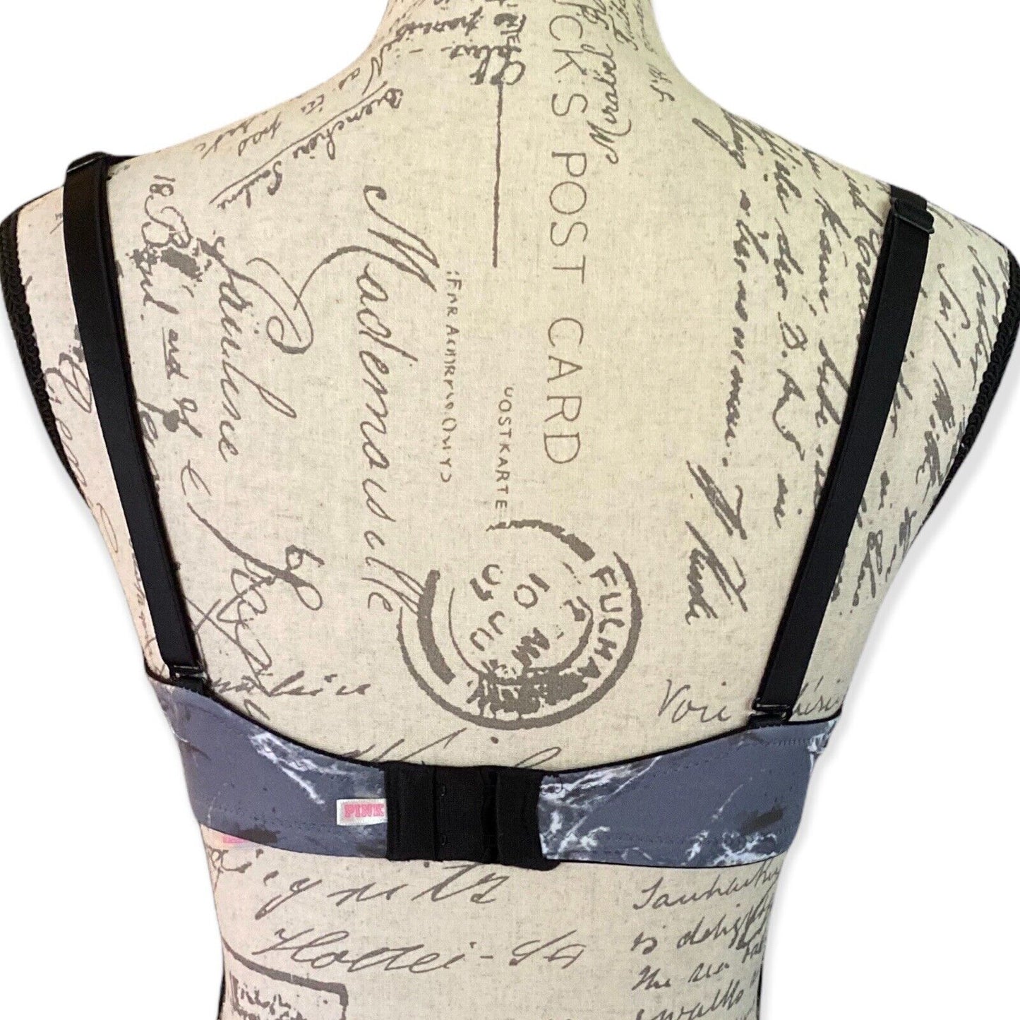 Back of gray bra on a mannequin with vintage-style text and stamp design