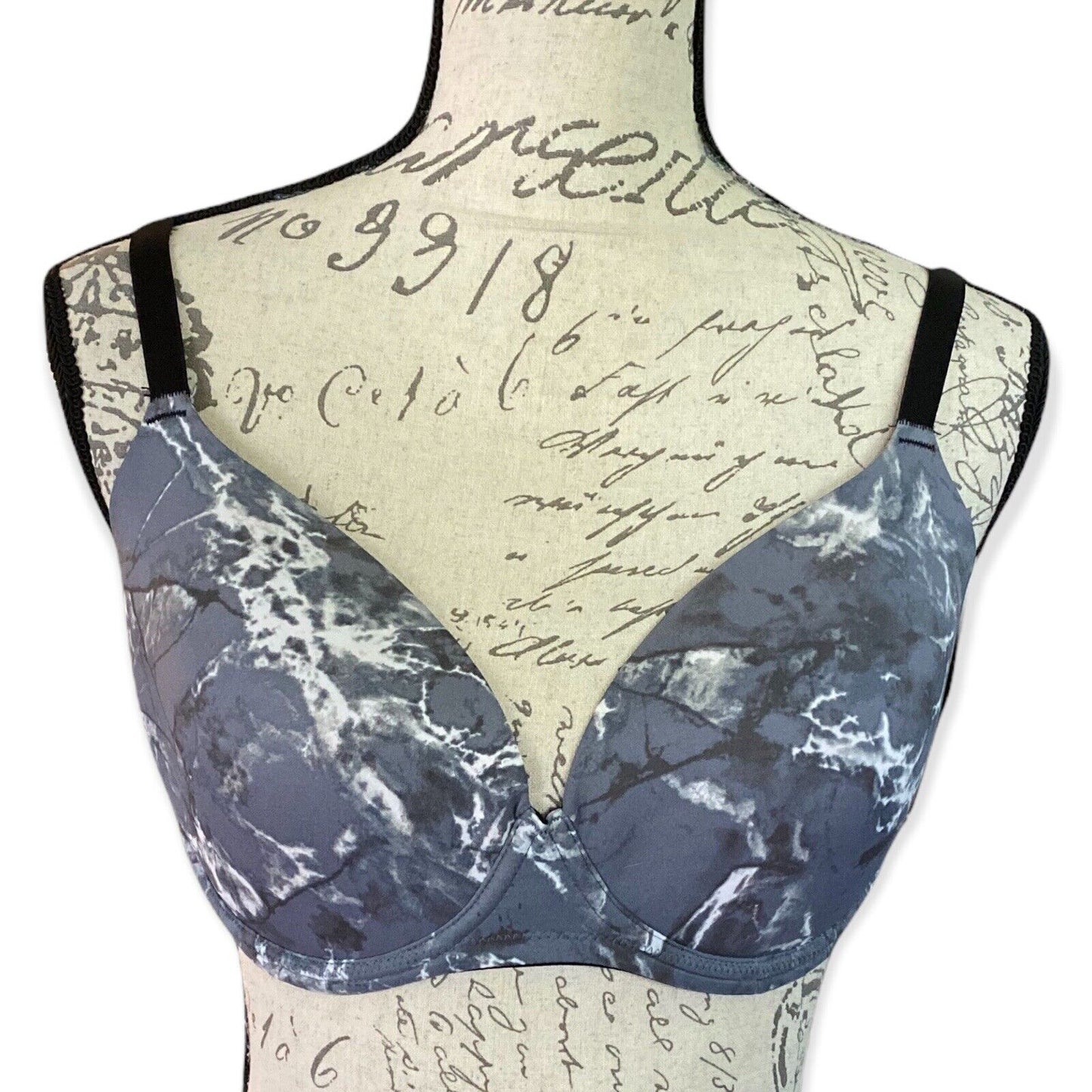 Front of gray bra on a mannequin with vintage-style text background