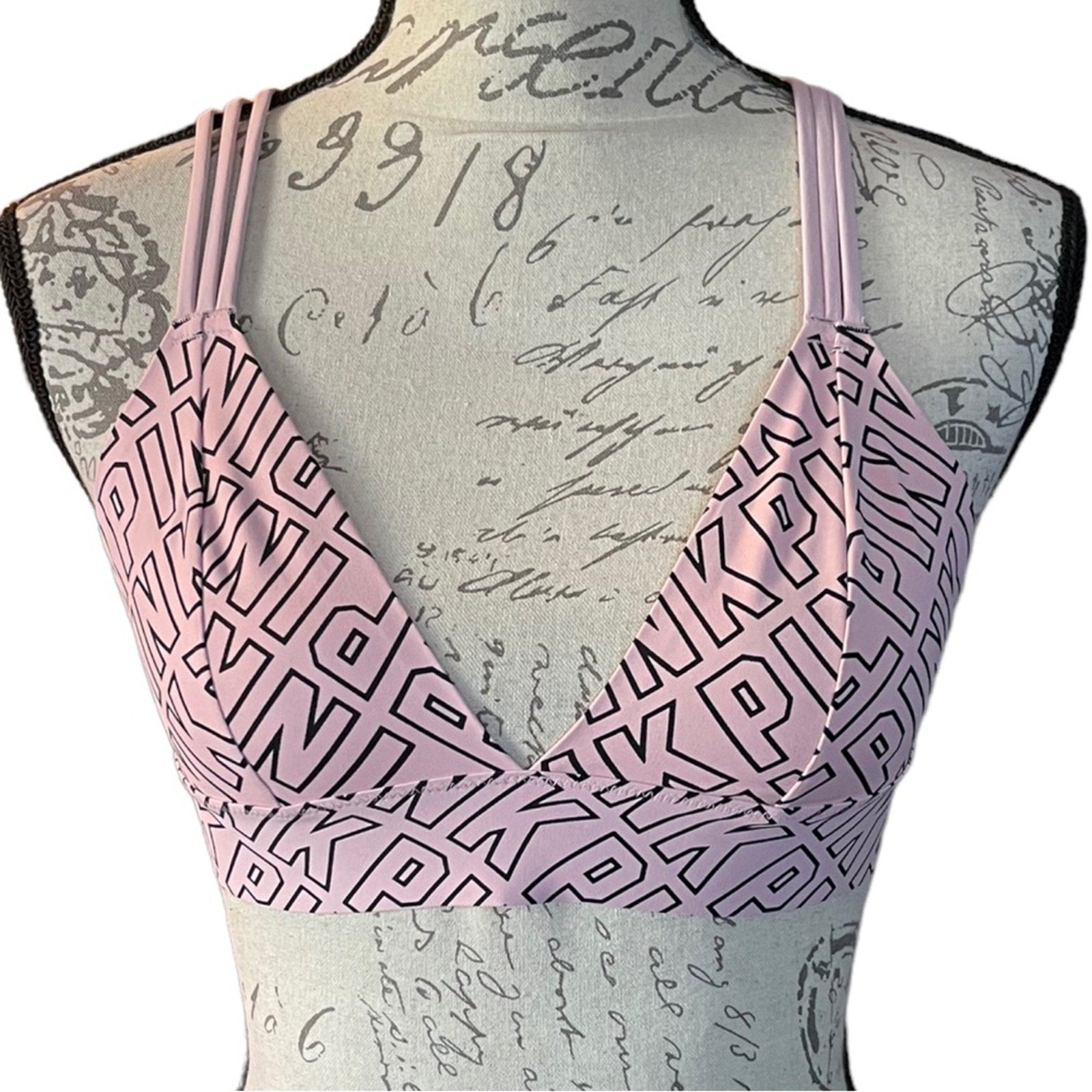 Pink bra with PINK written on it on a mannequin against a textured background