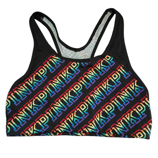 A black racerback sports bra featuring a repeating diagonal rainbow 'PINK' logo pattern across the front, shown against a plain white background.