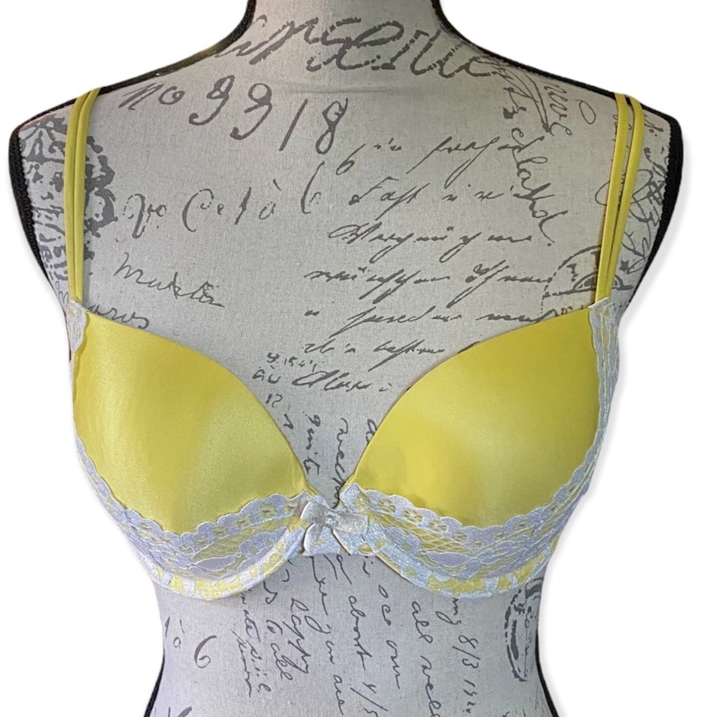 Front of Yellow bra on a mannequin with a script patterned background