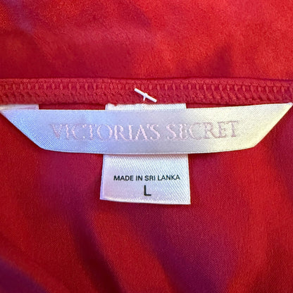 Close-up of a red garment's interior neck label showing the Victoria's Secret brand name, along with a size tag reading Made in Sri Lanka L.