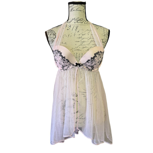 A sheer pink babydoll lingerie chemise with black lace cups and a black bow, displayed on a vintage-style printed mannequin torso against a white background.