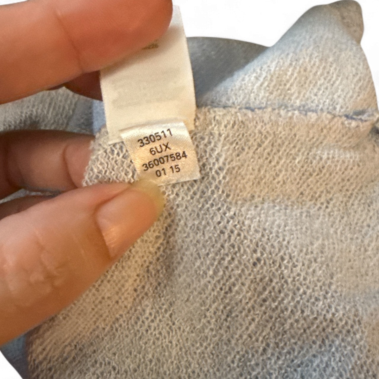 Close-up of a label on a woven fabric with a hand holding it.
