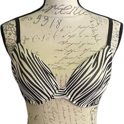 Black and white zebra-print bra displayed on a beige fabric dress form with a cursive script print, against a plain white background.