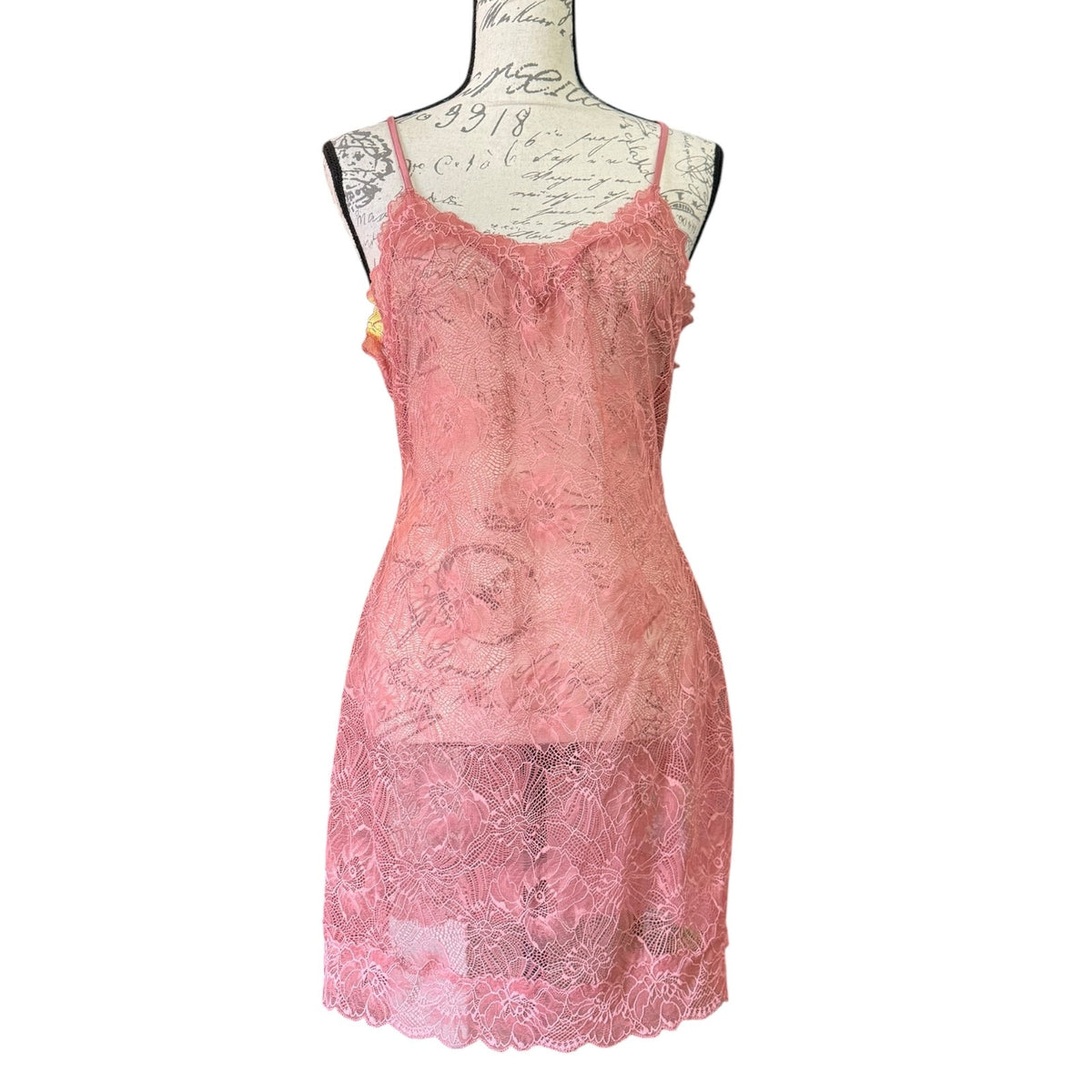 A pink floral lace slip dress lingerie with thin spaghetti straps, displayed on a vintage-style mannequin torso against a plain white background.