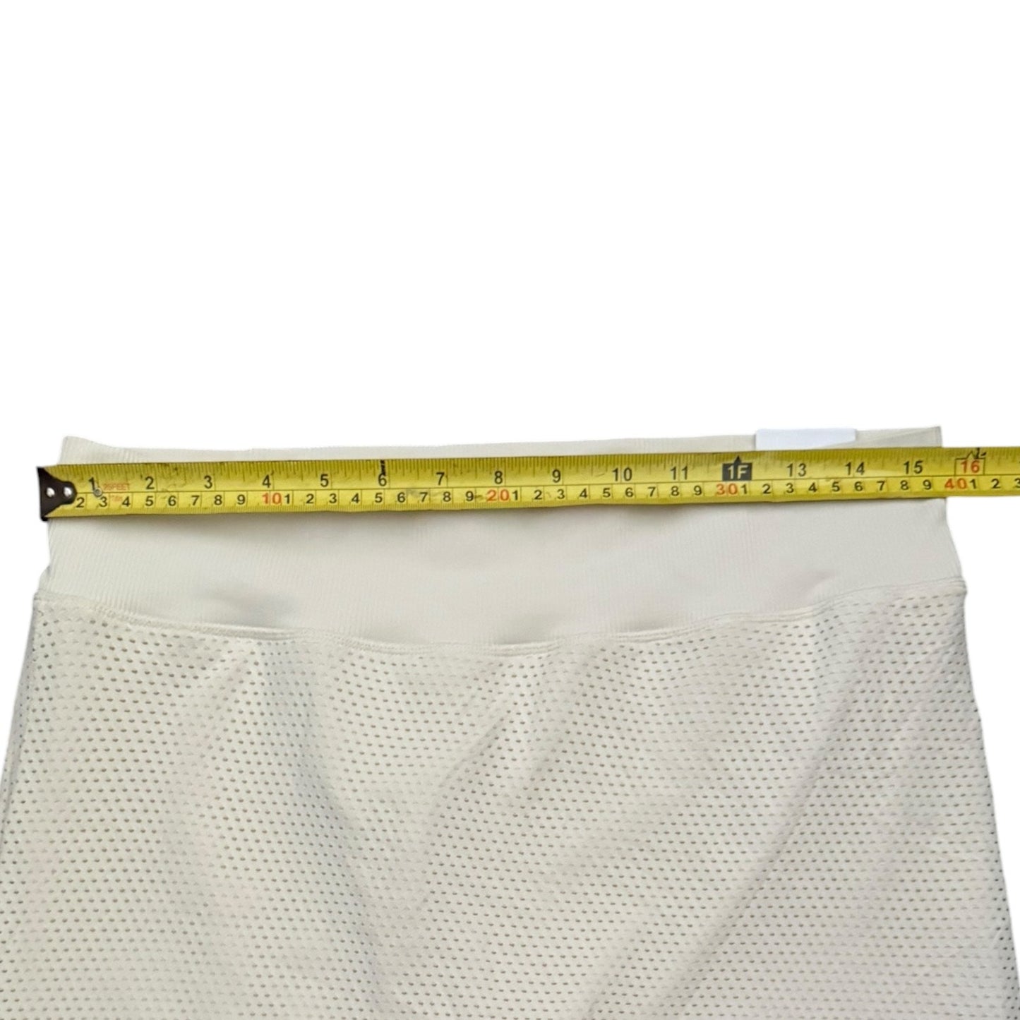 Mesh skort shown with a yellow tape measure stretched horizontally across the top edge to indicate size.